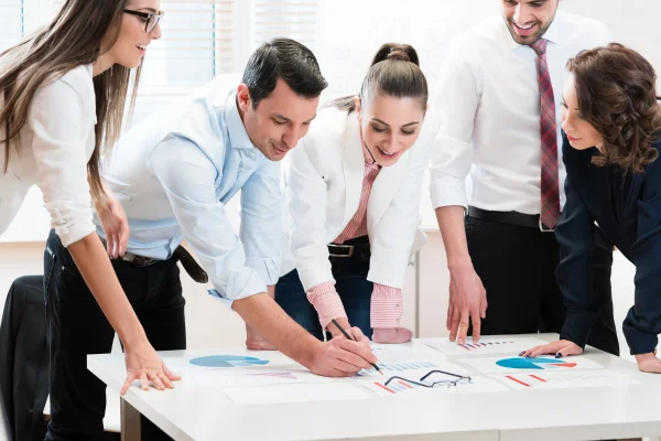 Equipo de cinco personas revisando gráficos sobre una mesa